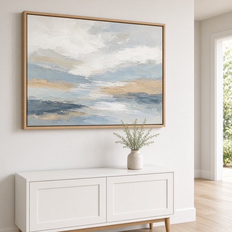 Single framed coastal canvas hung level above a console in a bright entryway